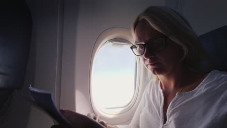 Young-Business-Woman-Looks-Through-Documents-In-Flight-Business-And-Travel