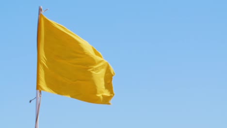 Yellow-Flag-Against-The-Blue-Sky