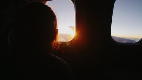 Little-Girl-Sitting-On-The-Plane-With-Delight-Looks-Out-The-Window-At-The-Rising-Sun