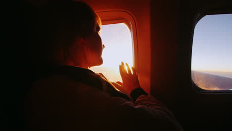 Young-Woman-Looking-At-The-Sun-From-The-Window-Of-An-Airliner