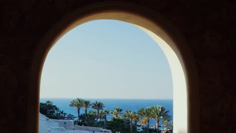 The-Window-Overlooking-The-Sea-And-The-Beach-With-Palm-Trees