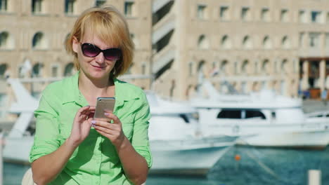 Woman-Typing-Sms-On-A-Tourist-City-Skyline-With-Yachts
