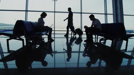 Silhouettes-Of-People-Waiting-For-A-Flight-Use-Gadgets-Walk-With-Hand-Held-Supplies
