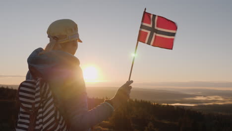 A-Traveler-With-The-Flag-Of-Norway-In-His-Hand-Meets-The-Sunrise-On-The-Top-Of-The-Mountain-Enjoys-T