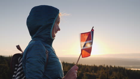 A-Traveler-With-The-Flag-Of-Norway-In-His-Hand-Meets-The-Sunrise-On-The-Top-Of-The-Mountain-Enjoys-T