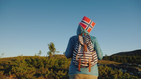 A-Tourist-With-A-Norwegian-Flag-In-A-Backpack-Walks-Through-The-Picturesque-Highlands-At-Dawn-Active
