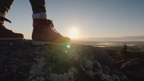 The-Traveler's-Feet-At-The-Top-Of-The-Peak-Through-Them-Shines-The-Rising-Sun-And-Beautiful-Landscap