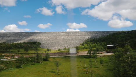 View-From-A-Car-Window-At-A-Landscape-In-Norway-With-A-Large-Stone-Dam