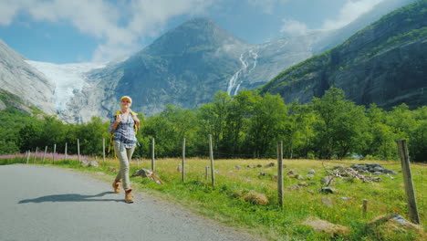 An-Active-Successful-Woman-Travels-Through-Norway-Walks-Against-The-Backdrop-Of-Mountains-With-A-Bac