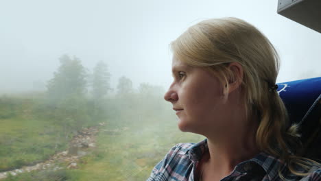 A-Woman-Looks-Out-The-Window-Of-A-Bus-To-A-Forest-Covered-With-Thick-Fog-Traveling-In-Norway