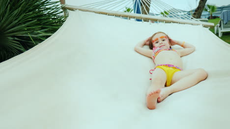 A-Little-Cool-Girl-In-A-Bikini-With-A-Painted-Face-Rests-On-A-Hammock-During-The-Summer-Holidays