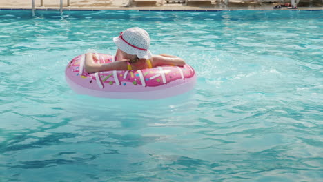 A-Funny-Little-Girl-In-A-Panama-Skates-On-An-Inflatable-Circle-In-A-Large-Pool-In-A-Hotel-On-The-Sea