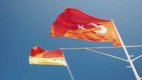 Red-With-Crescent-Turkey-Flag-And-Rescue-Service-Flag-Against-The-Blue-Sky-Beach-Season-In-Turkey