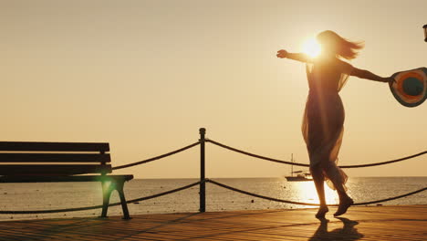The-Woman-Is-Happily-Spinning-On-The-Pier-Holding-A-Hat-In-Her-Hand-The-Sunrise-Meets-Happy-Woman-On