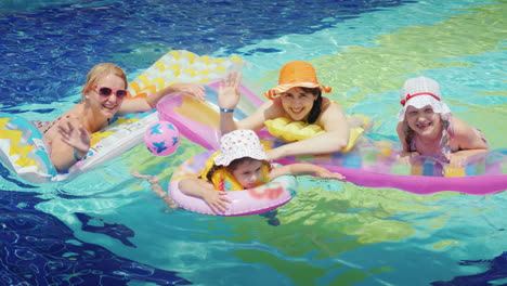 Happy-Parents-With-Children-Are-Swimming-In-The-Pool-Hold-On-To-An-Air-Mattress-Look-At-The-Camera-4