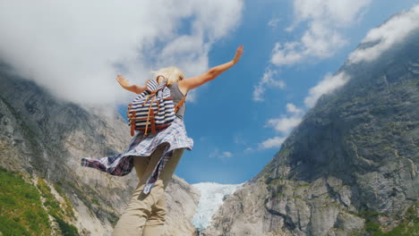 A-Healthy-Woman-Raised-Her-Hands-Joyfully-Standing-On-The-Background-Of-The-Brixdal-Glacier-In-Norwa