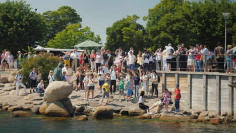 A-Crowd-Of-Tourists-Is-Photographed-Near-The-Famous-Statue-Of-The-Little-Mermaid-In-Copenhagen
