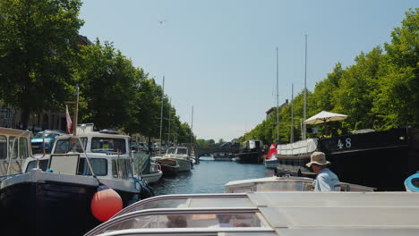 Recorrido-Por-Los-Canales-De-Copenhague,-Un-Bote-Con-Turistas-Navegando-A-Lo-Largo-De-Un-Estrecho-Canal-Por-Delante-Del