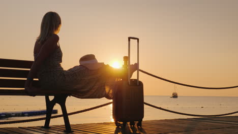 A-Young-Girl-Is-Waiting-To-Board-A-Ship-In-The-Early-Morning-On-A-Sea-Pier-With-Luggage
