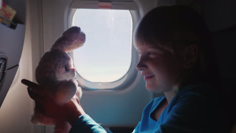 The-Girl-Is-Traveling-On-A-Plane-With-Her-Favorite-Toy-Happy-Childhood-And-Vacation-With-The-Baby-Co