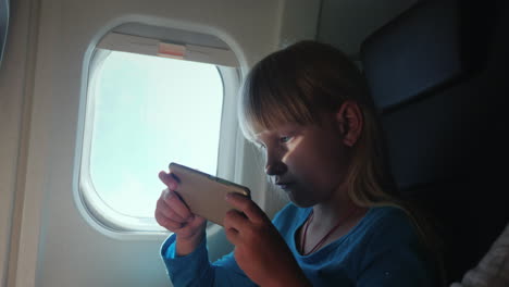 A-Blonde-Girl-Plays-On-A-Smartphone-While-Flying-In-An-Airplane