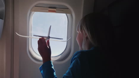 The-Girl-Is-Playing-With-A-Small-Toy-Airplane-In-The-Cabin-Of-The-Airliner-Baby-Dreams-Concept-4k-Vi