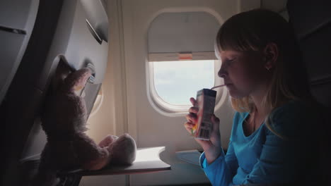 The-Child-In-The-Cabin-Of-The-Plane---Drinking-Juice-From-The-Tube-With-Her-Flying-Toy---A-Hare-4k-V