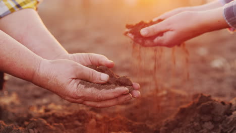 Hands-Of-Two-Farmers-Hold-Soil-Over-Plowed-Field-Organic-Production-From-Your-Farm