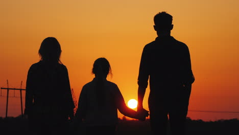 Family-Of-Three-Admiring-The-Orange-Sunset-Over-The-City-Rear-View
