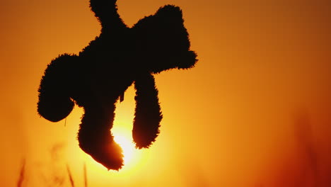 A-Child-Is-Holding-A-Murderous-Bear-By-The-Paw-Against-The-Setting-Sun-And-Orange-Sky