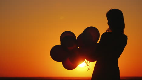 Silhouette-Of-A-Woman-With-Balloons-At-Sunset-Nostalgia-Concept