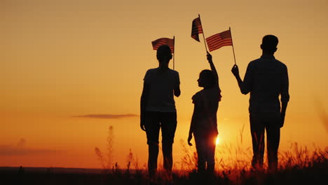 Family-With-Child-Waving-Us-Flags-At-Sunset-Rear-View