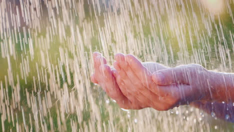 Ein-Mann-Hält-Seine-Hände-Im-Strömenden-Regen-Wassertropfen-Fliegen-Auseinander-Kühles-Und-Sauberes-Wasserkonzept-Langsam