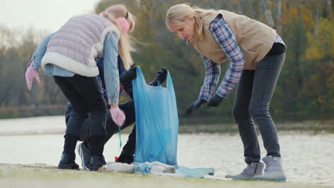 A-Woman-With-Children-Picks-Up-Trash-On-The-Lake-Volunteers-Collect-Plastic-Waste