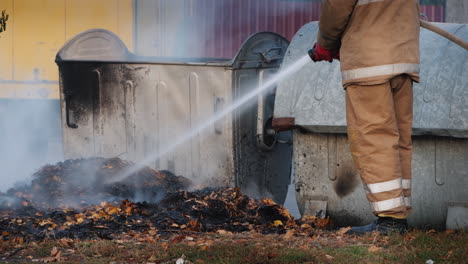 Firefighter-Puts-Out-A-Fire-Near-Garbage-Bins-After-A-Riot