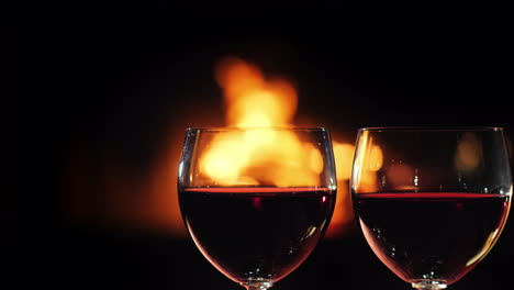Two-Glasses-Of-Red-Wine-Against-The-Background-Of-The-Fireplace-Where-The-Fire-Burns