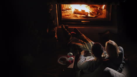 A-Young-Couple-Admires-The-Fire-In-The-Fireplace-Sitting-Next-To-Them-And-Drinking-Tea-Romantic-Dinn