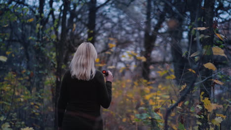 Frightened-Woman-Walks-Through-The-Woods-At-Dusk-Illuminates-Her-Way-With-A-Flashlight