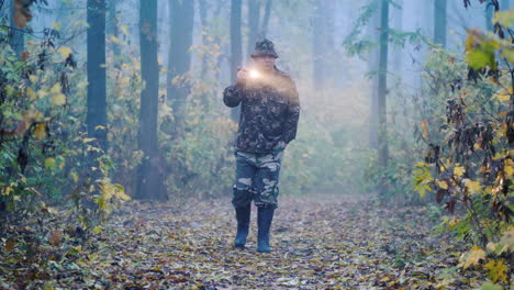 A-Man-In-Camouflage-Is-Walking-Through-The-Forest-Lighting-His-Way-In-The-Fog-Search-For-The-Missing