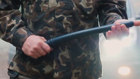 A-Man-In-Camouflage-With-A-Rubber-Baton-Beats-His-Arm