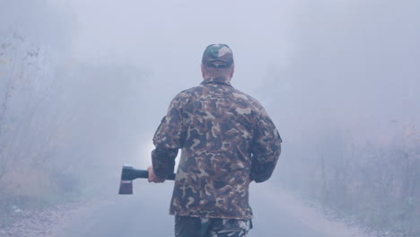 Aggressive-Man-With-An-Ax-Is-Walking-In-The-Fog-Towards-The-Car