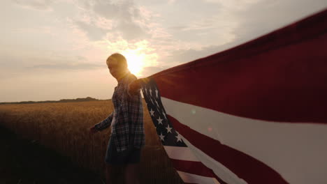 First-Person-View-Of-A-Woman-Carrying-The-Usa-Flag-At-One-Of-The-Edges-Go-Near-The-Wheat-Field-At-Su