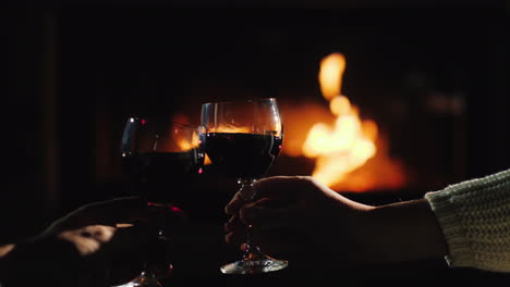 Clink-Glasses-With-Wine-Against-The-Background-Of-The-Fireplace-Where-The-Fire-Is-Burning