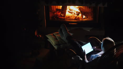 A-Woman-Is-Resting-By-The-Fireplace-Using-A-Tablet-View-From-Above