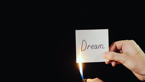 Hand-Holds-Burning-Paper-With-Inscription-Dream