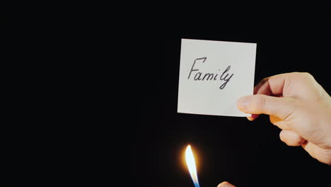Hand-Holds-Burning-Paper-With-Inscription-Family