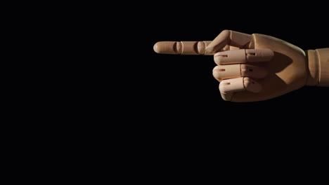 Wooden-Hand-Points-with-Finger-On-Black-Background