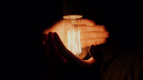 A-Man-Holds-His-Hands-Around-An-Electric-Luz-Bulb