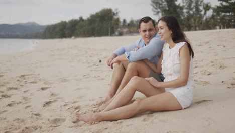 Young-lovers-tourists-sitting-on-beach
