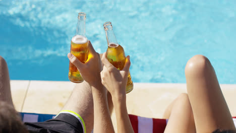 Couple-relaxing-at-the-pool-with-beers